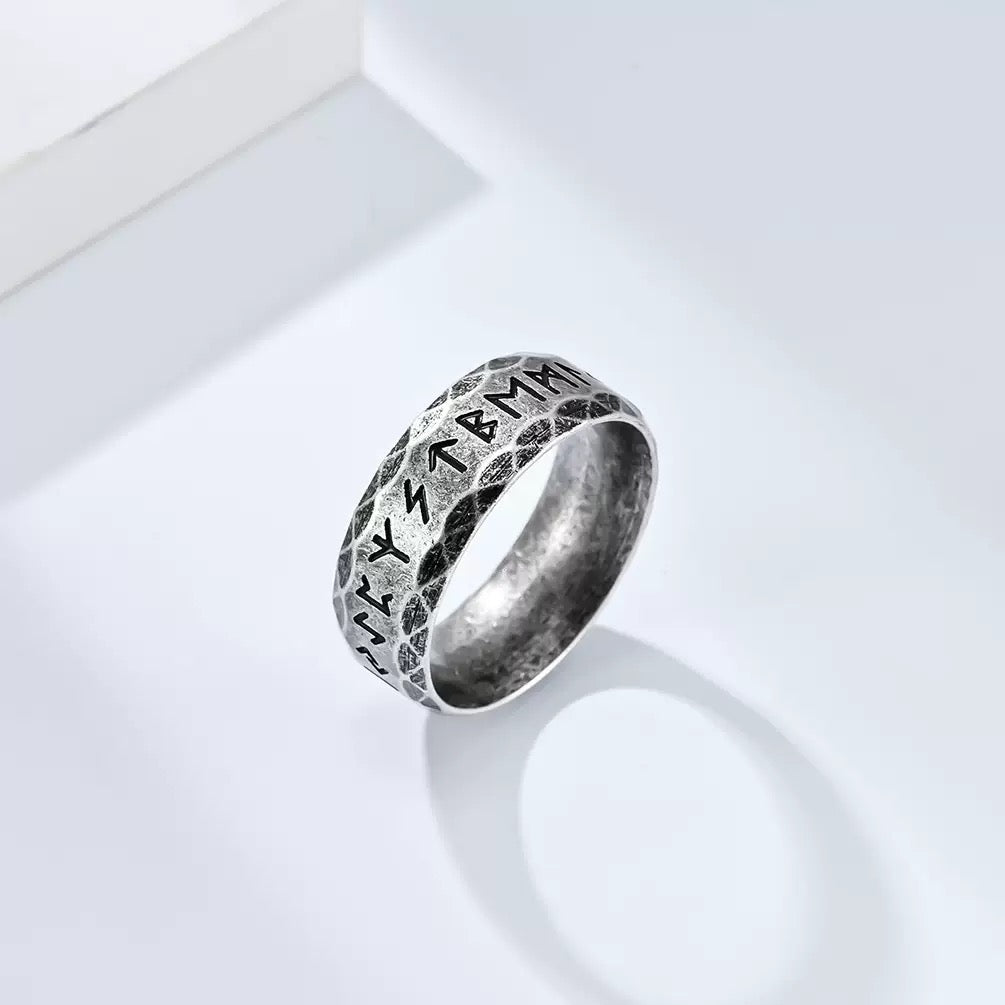 Silver ring with engraved symbols on a white background