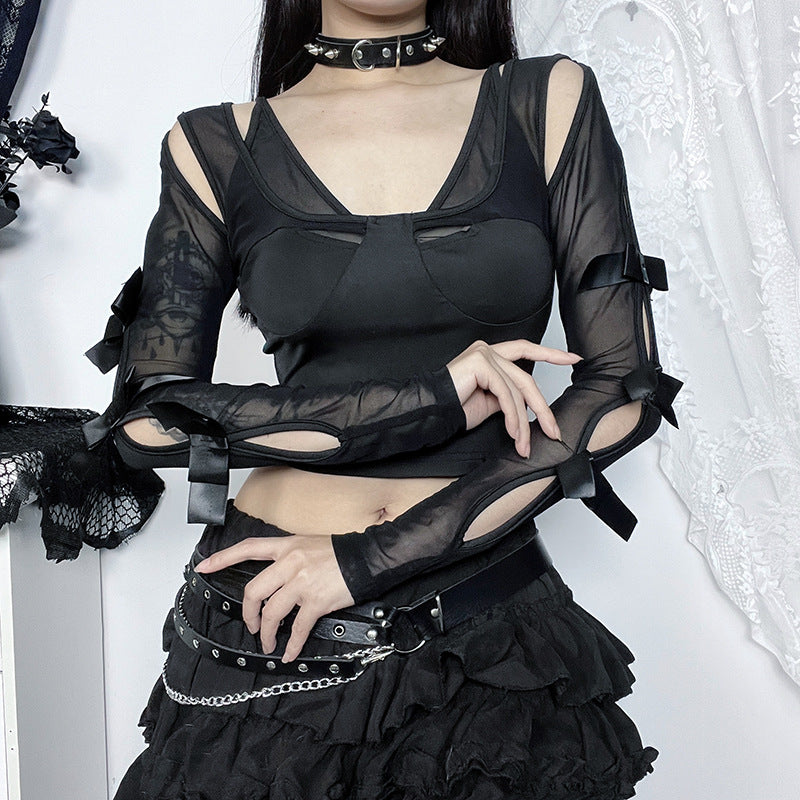 Person wearing a black outfit with sheer sleeves and ruffled skirt against a white background