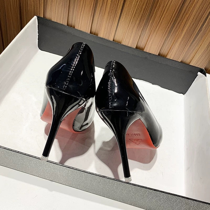Black high-heeled shoes in a box with a wooden background