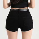 Black denim shorts with a studded belt worn by a person on a plain background