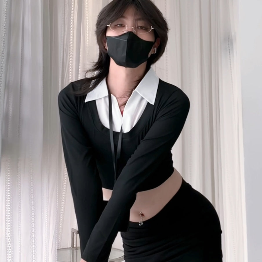 Femboy wearing a black outfit with a white collar and black mask against a neutral background