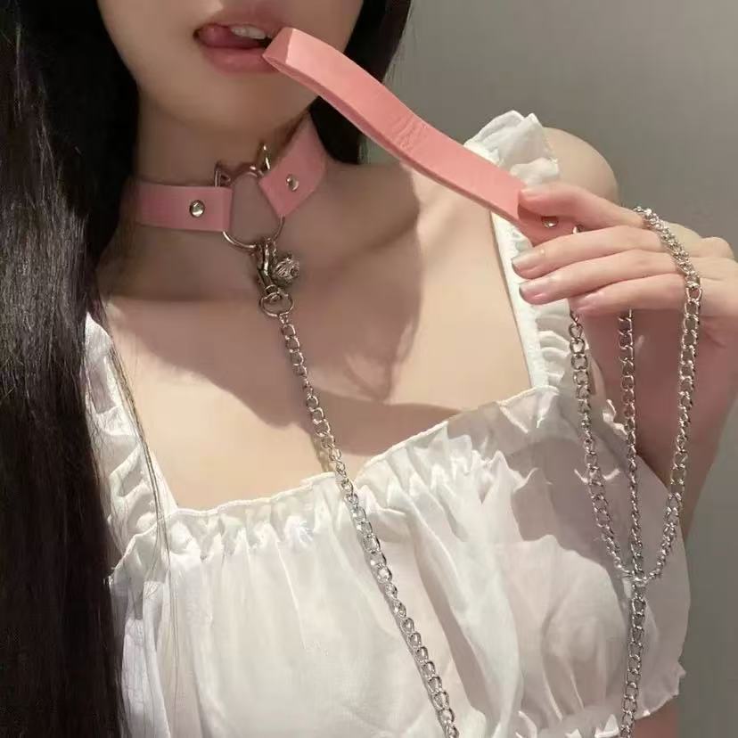Person wearing a pink choker with a belt, holding a pink leather chain.