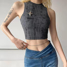 Person wearing a gray distressed crop top and blue jeans against a neutral background