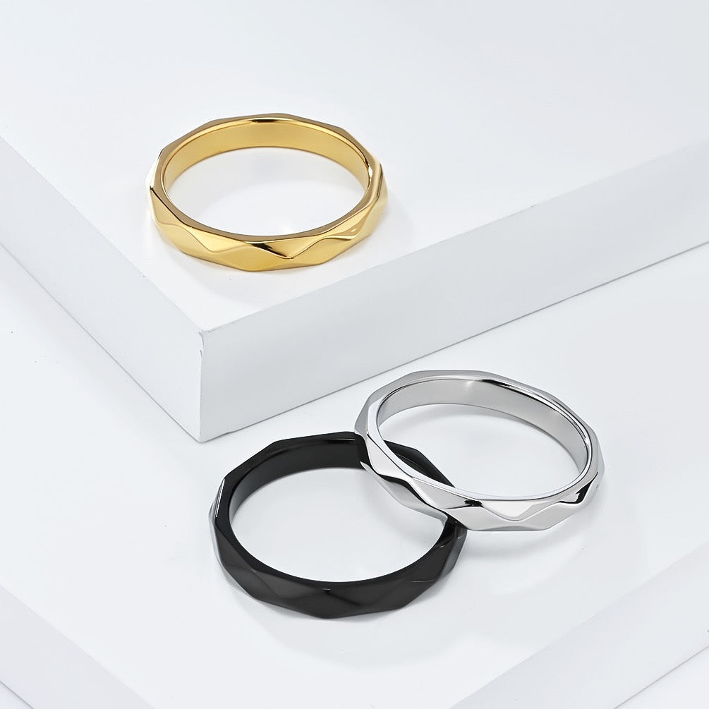 Three rings in gold, silver, and black on a white surface