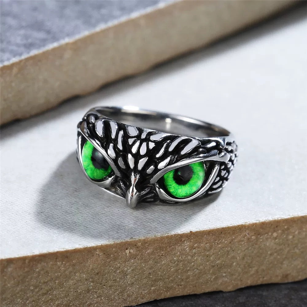 Silver owl ring with green eyes on a white surface