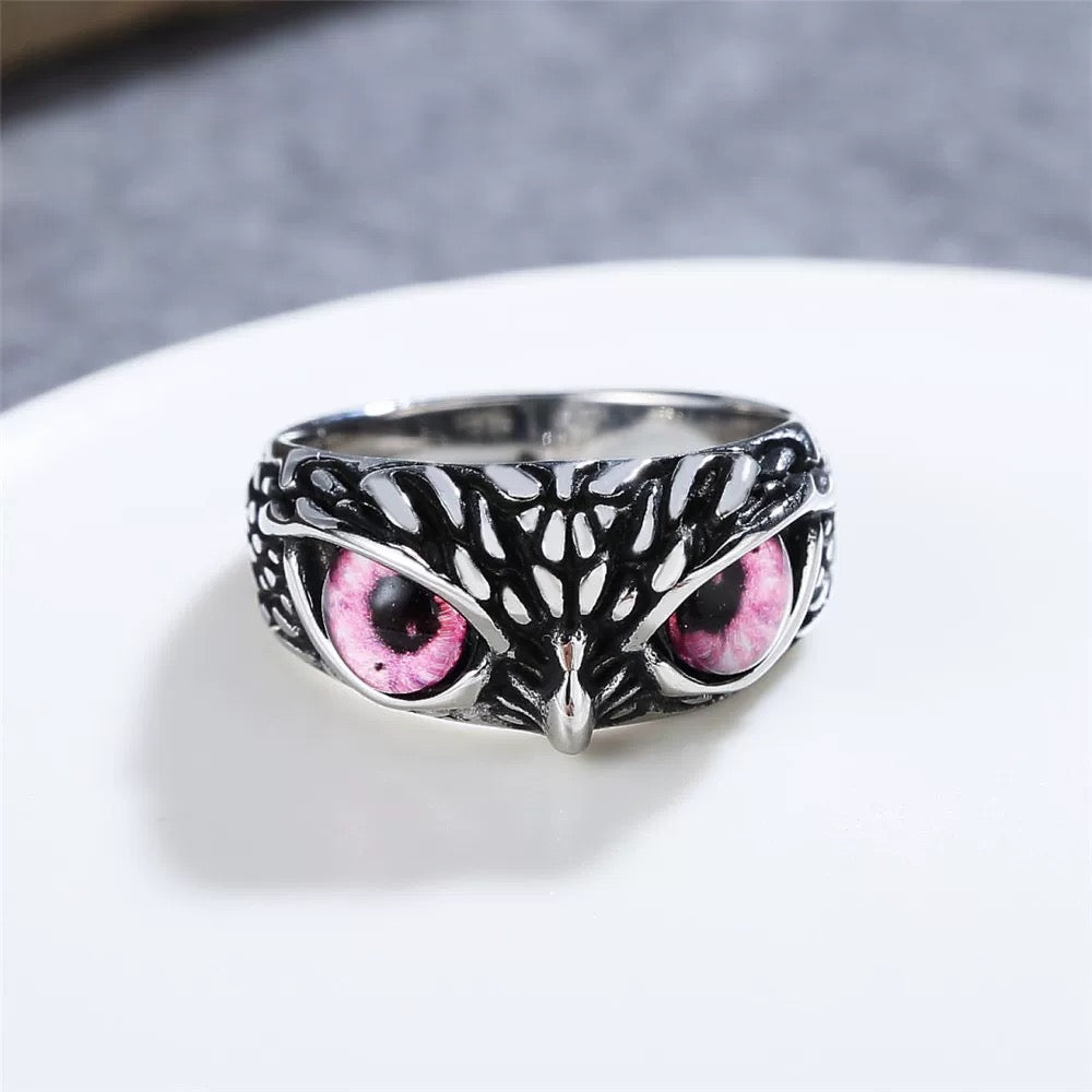 Silver owl ring with pink eyes on a white surface