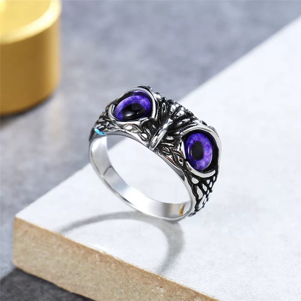 Silver ring with purple gemstones on a light gray surface
