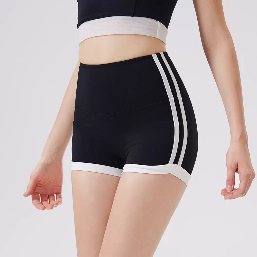 Black athletic shorts with white stripes on a plain background