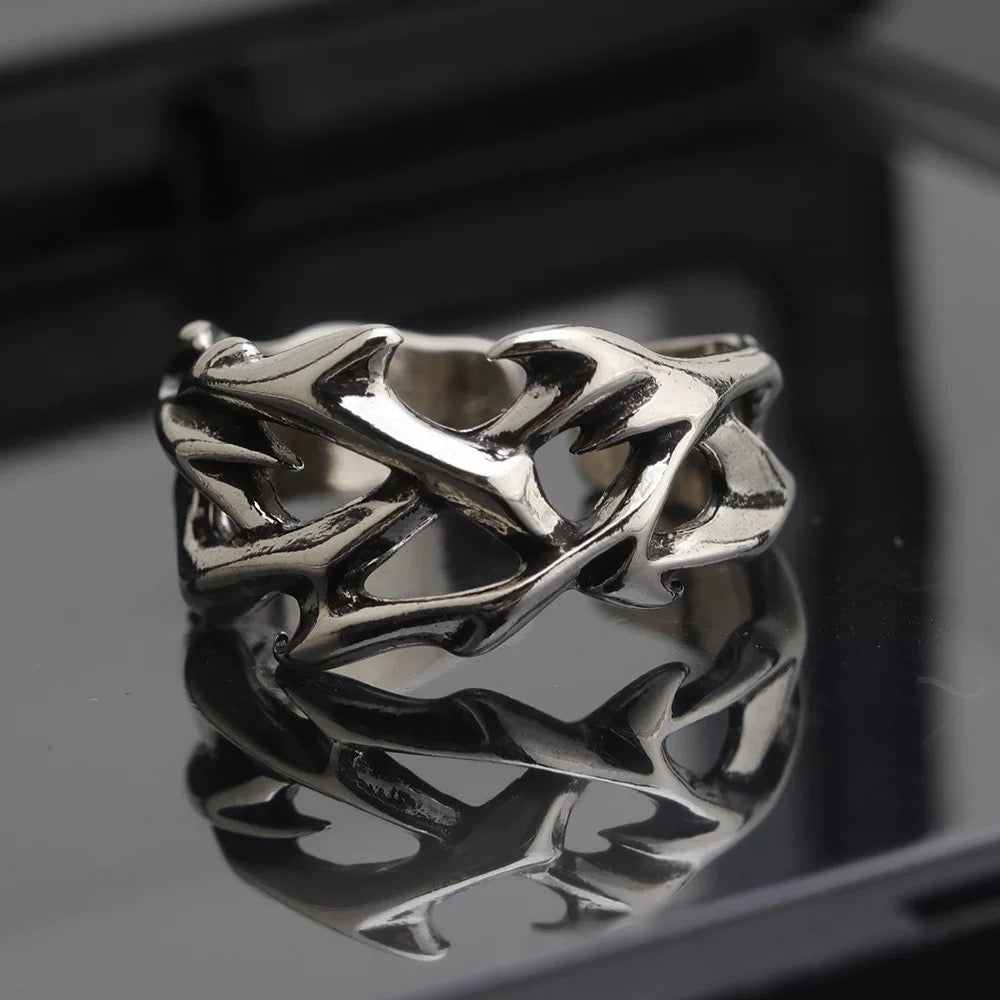 Silver thorny vine stainless steel ring with a geometric design on a reflective black surface