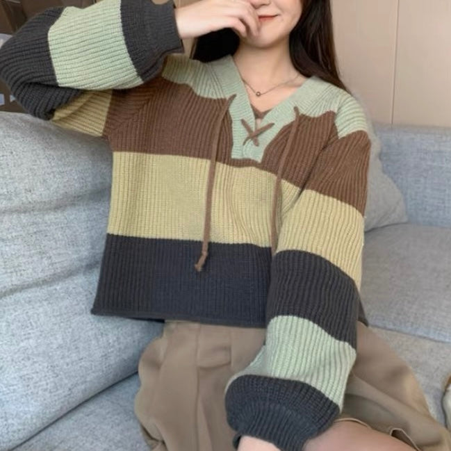 A femboy wearing a v neck lace up color block sweater