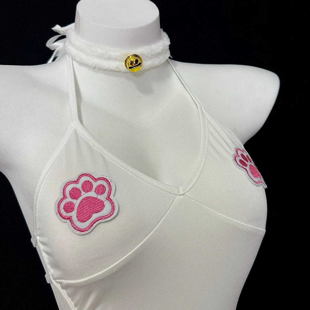 White garment with pink paw prints on a mannequin against a black background