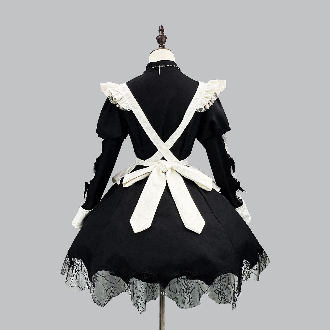 Black and white gothic maid dress on a mannequin against a gray background back