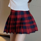 Red and navy plaid skirt worn by a person on a neutral background