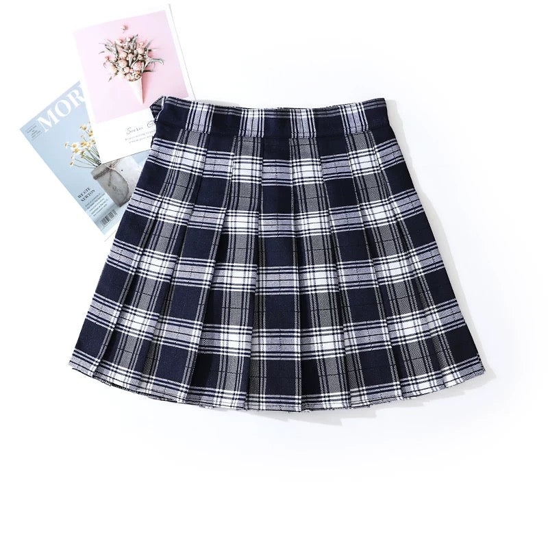 Plaid skirt on a white background with a magazine and flowers.