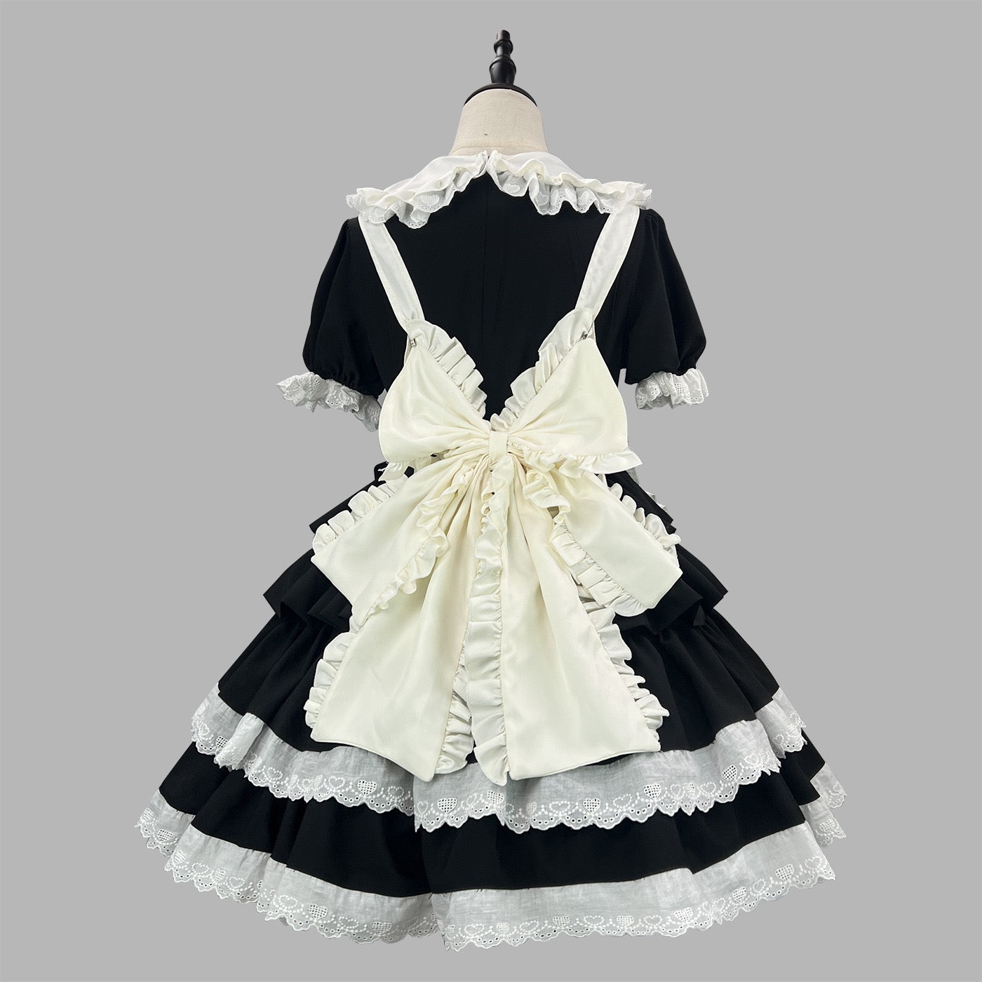 Black and white dress with ruffled apron on a mannequin against a gray background