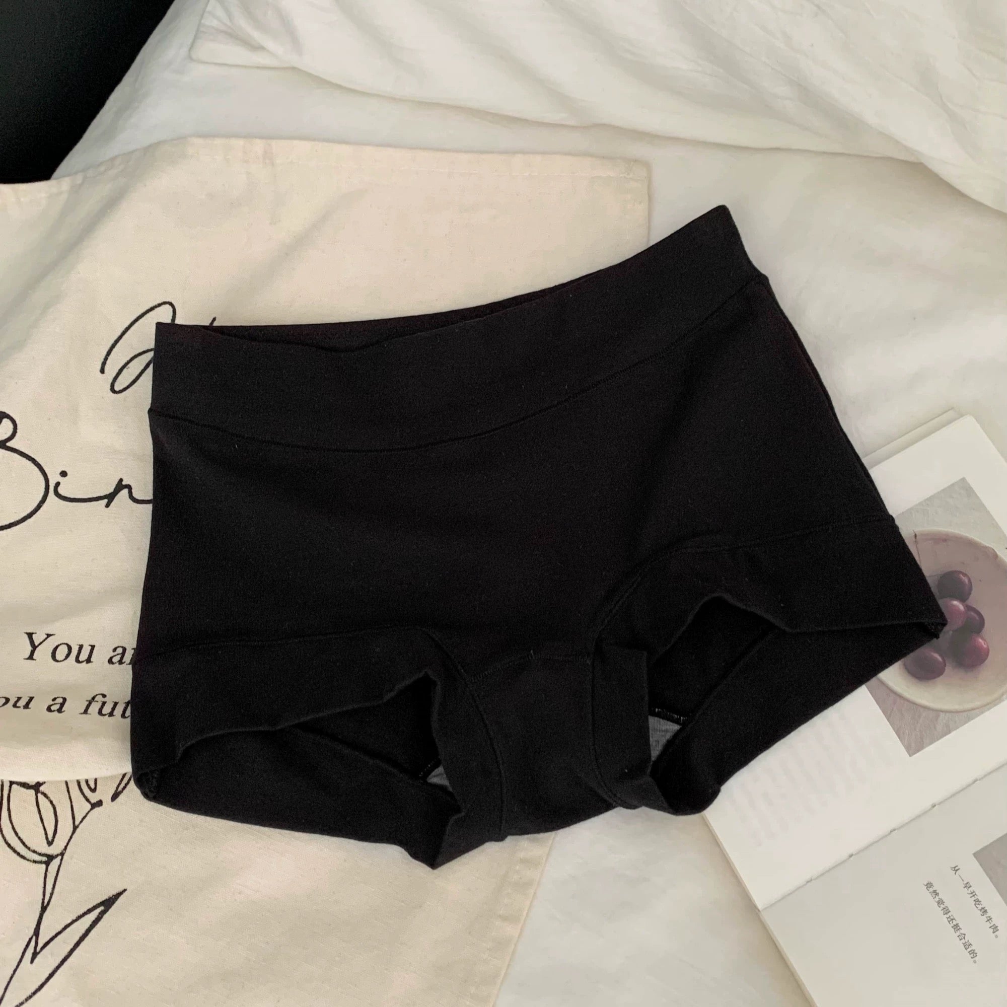 Black cotton boyshorts on a white surface with text and images.