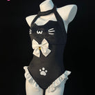 A black cat-themed halter bodysuit displayed on a white mannequin torso against a black background. The bodysuit features white cat face details, a large white bow with a small gold center, white paw print, and white ruffled trim at the waist.
