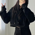Femboy wearing a black crop hoodie and pants against a neutral background