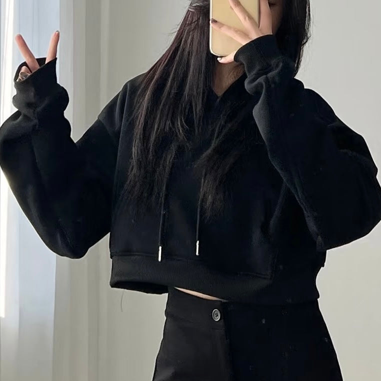 Femboy wearing a black crop hoodie and pants against a neutral background