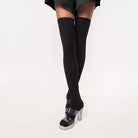Black thigh-high socks with clear high-heeled shoes on a white background