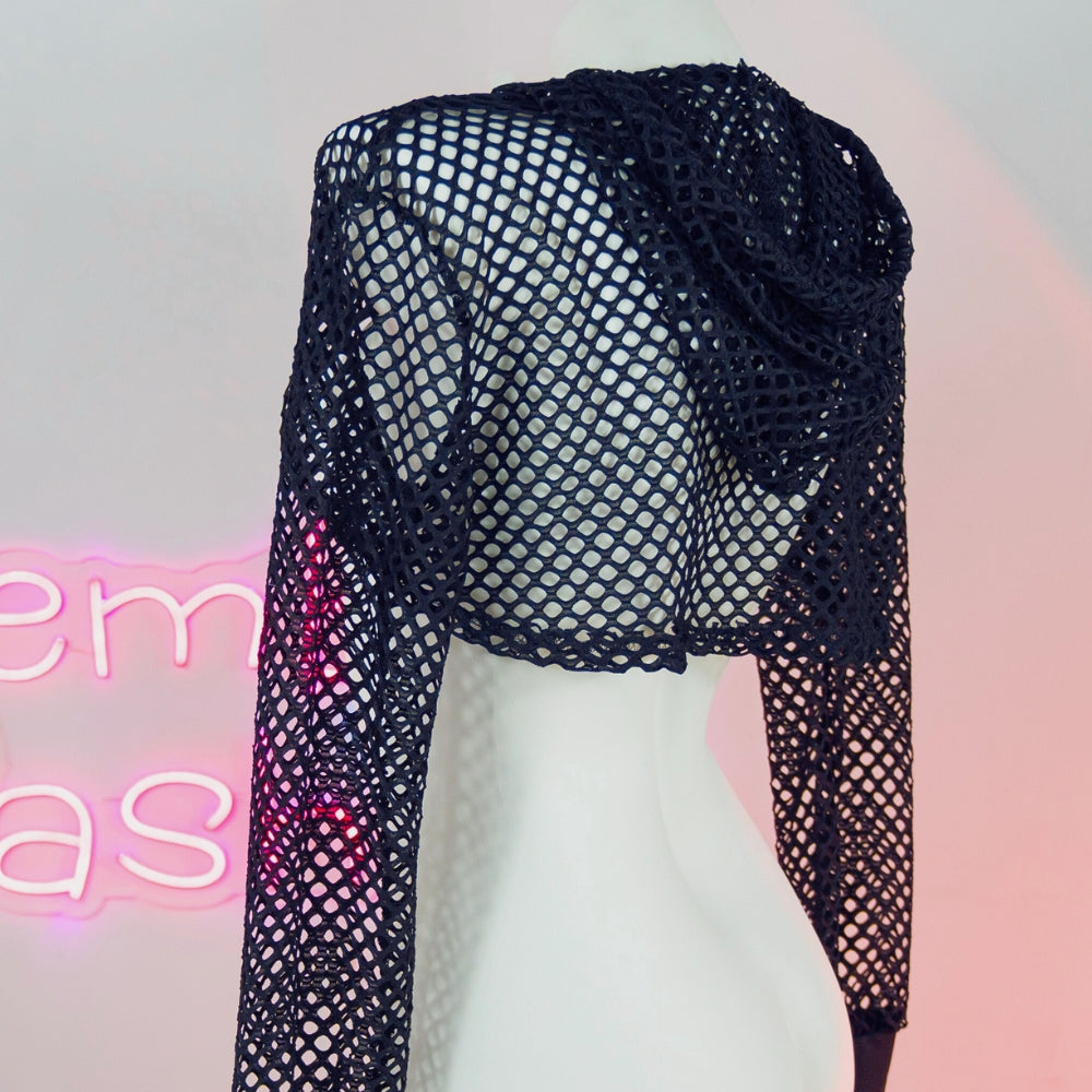 Black fishnet top on a mannequin with a neon sign in the background