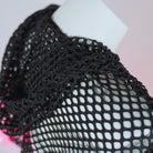 Close-up of black fishnet fabric on a mannequin arm.