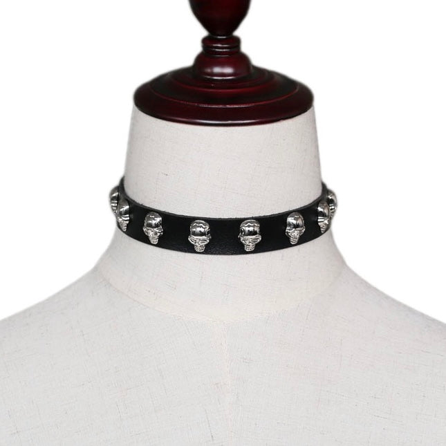 A black faux-leather choker collar decorated with silver skull studs, displayed on a white fabric mannequin bust.