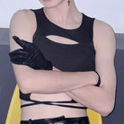 Person wearing a black sleeveless top with cut-out design and black gloves, standing against a plain background.
