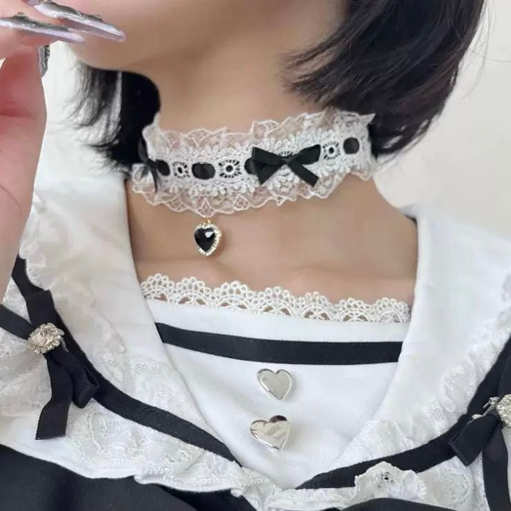 Close-up of a person wearing a lace choker with black bows and heart-shaped pendants.