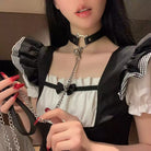 Person wearing a black choker with a cat design, holding a chain accessory.