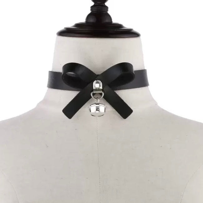Black leather choker with a silver bell on a mannequin bust.