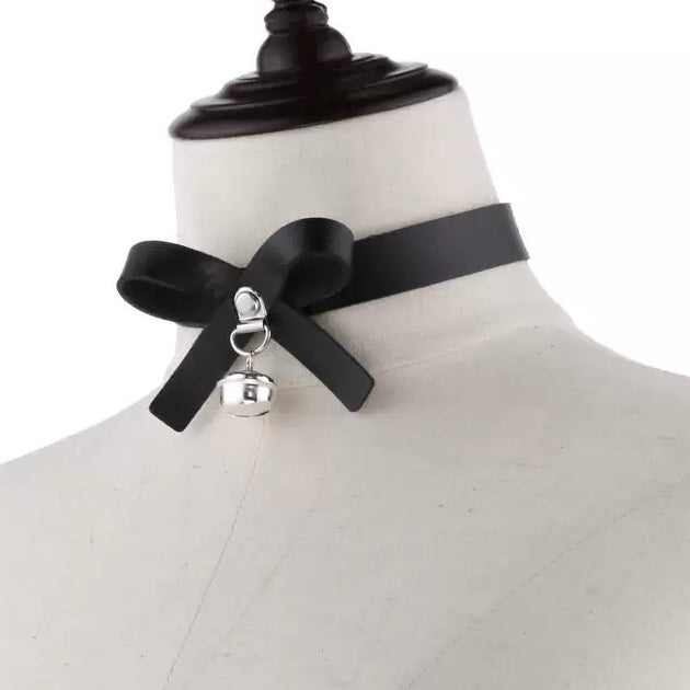 Black choker with a bow and bell charm on a mannequin.