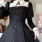 Person wearing a black dress with lace details in an indoor setting