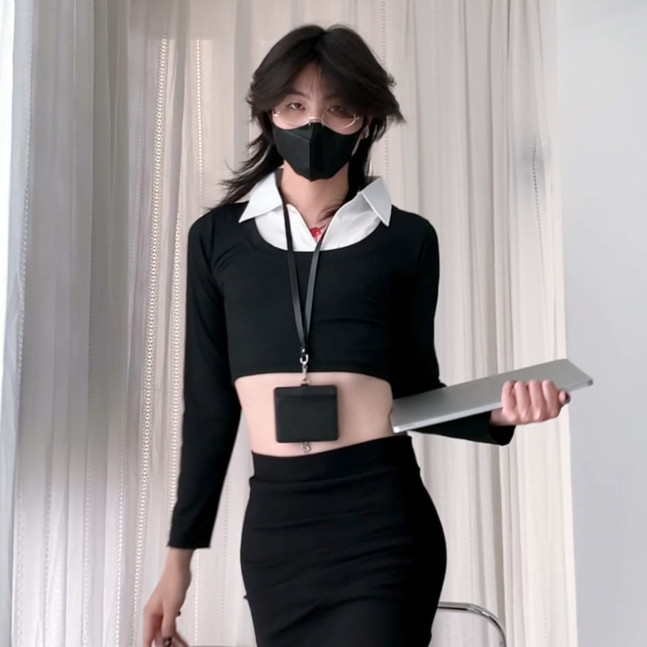 Femboy wearing a black outfit with a white shirt, holding a tablet, against a light curtain background.
