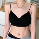 A sissy wearing a black spaghetti-strap camisole crop top with a scoop neckline, paired with gray sweatpants and a silver chain necklace.