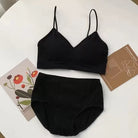 A two-piece black ribbed lingerie set consisting of a camisole-style bralette with thin straps and matching high-waisted briefs, arranged on a white surface with decorative cards.