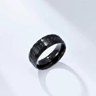 Black ring with engraved design on a light gray background