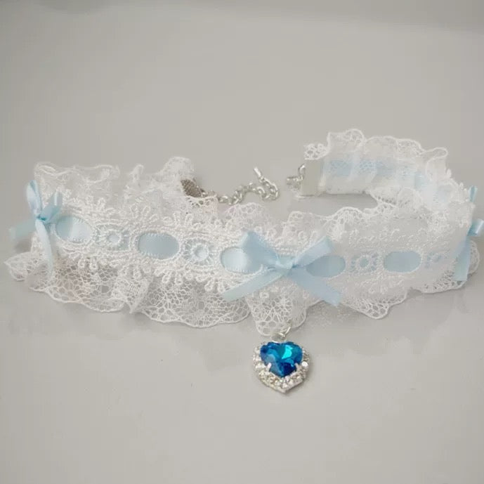 White lace choker with blue heart charm on a gray background