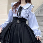 Woman wearing a blue long-sleeve top with cut-out design and black pants on a white background