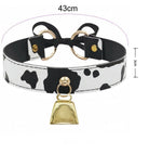 Cow print collar with black and white cow spots, gold-tone hardware, a bow detail, and a small hanging bell, shown with dimension labels indicating 43cm width and 3cm height.