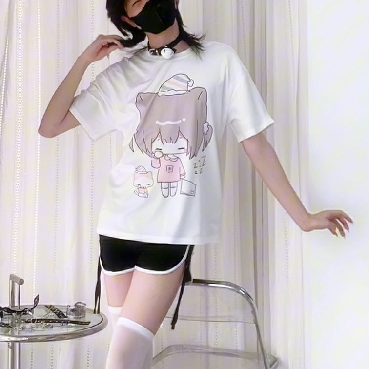 Person wearing a white t-shirt with a cartoon character design, sitting on a chair.