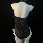 Black halter bodysuit with white ruffled trim, displayed on a white mannequin against a black background.