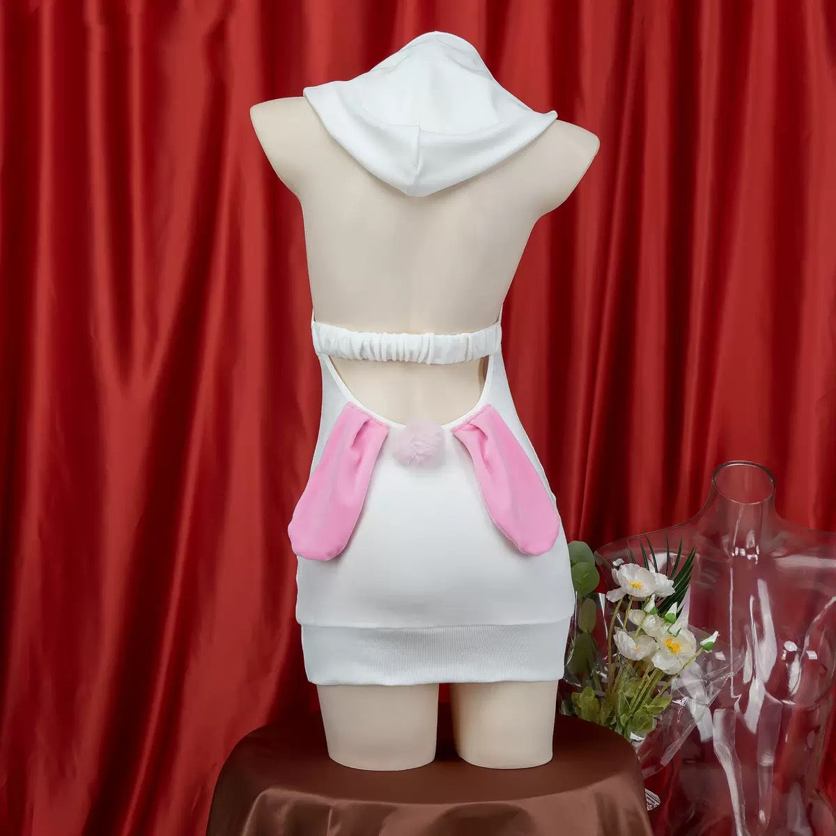 Mannequin wearing a white cute sleeveless bunny lingerie with a red curtain background