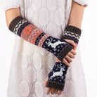 Knitted arm warmers with deer pattern worn by a person on a white lace background