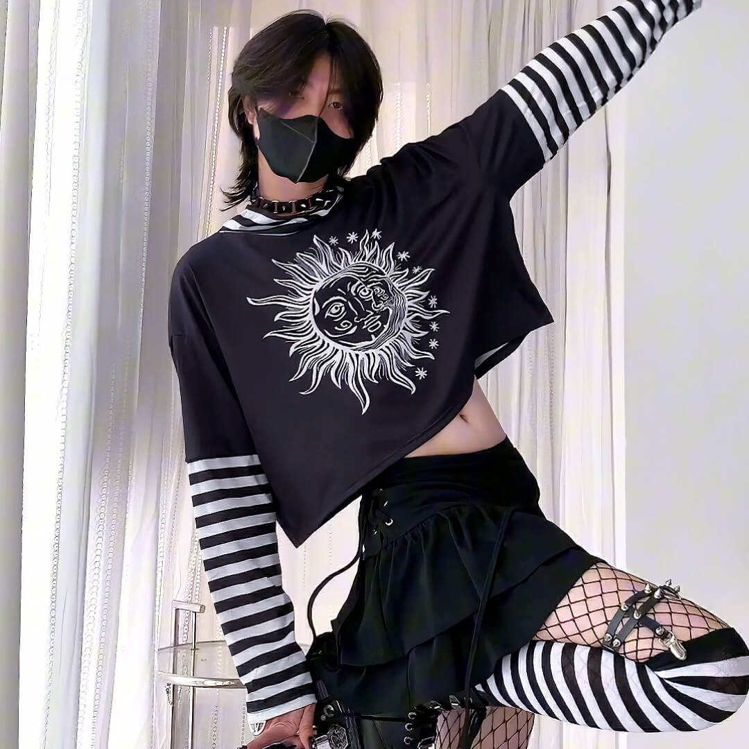 Person wearing a black long-sleeve shirt with a sun and moon design, black skirt, and striped leggings.