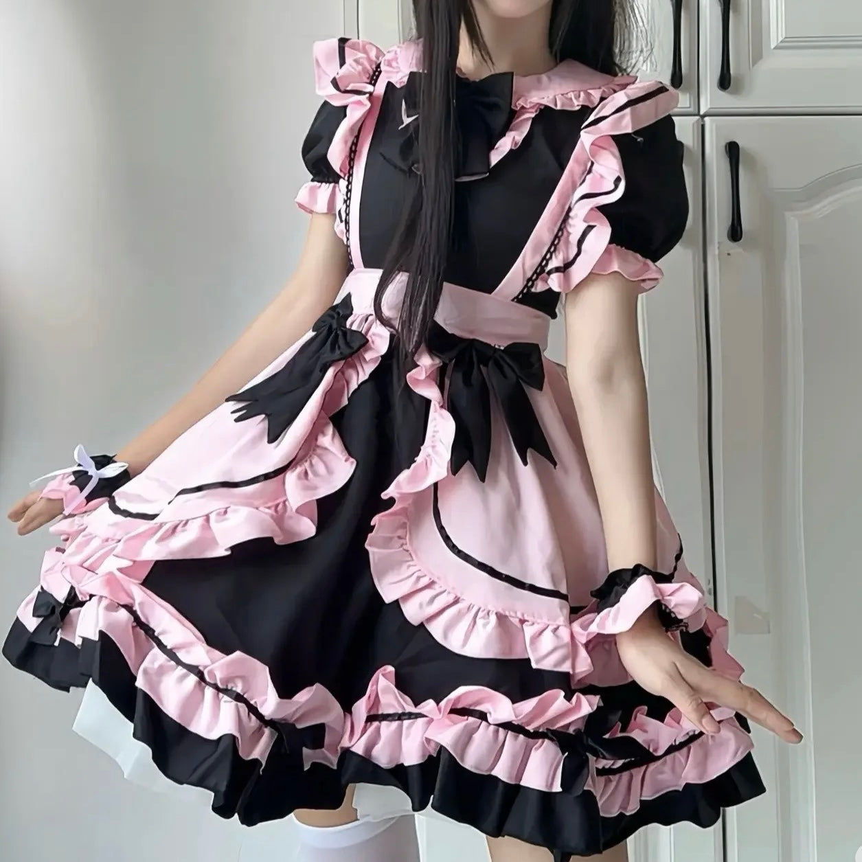 Person wearing a black and pink maid outfit taking a selfie.