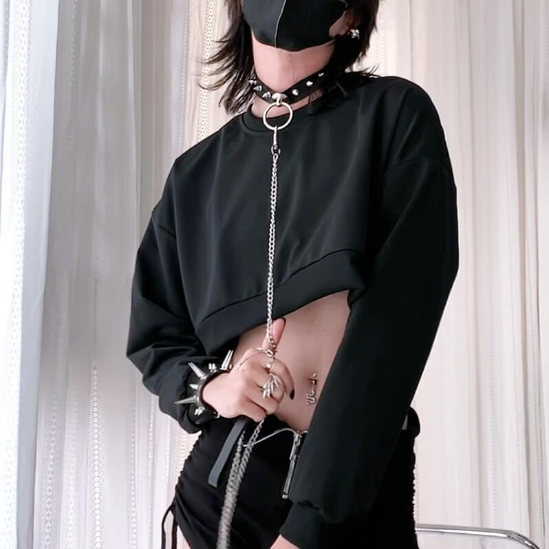 Person wearing a black outfit with accessories against a neutral background