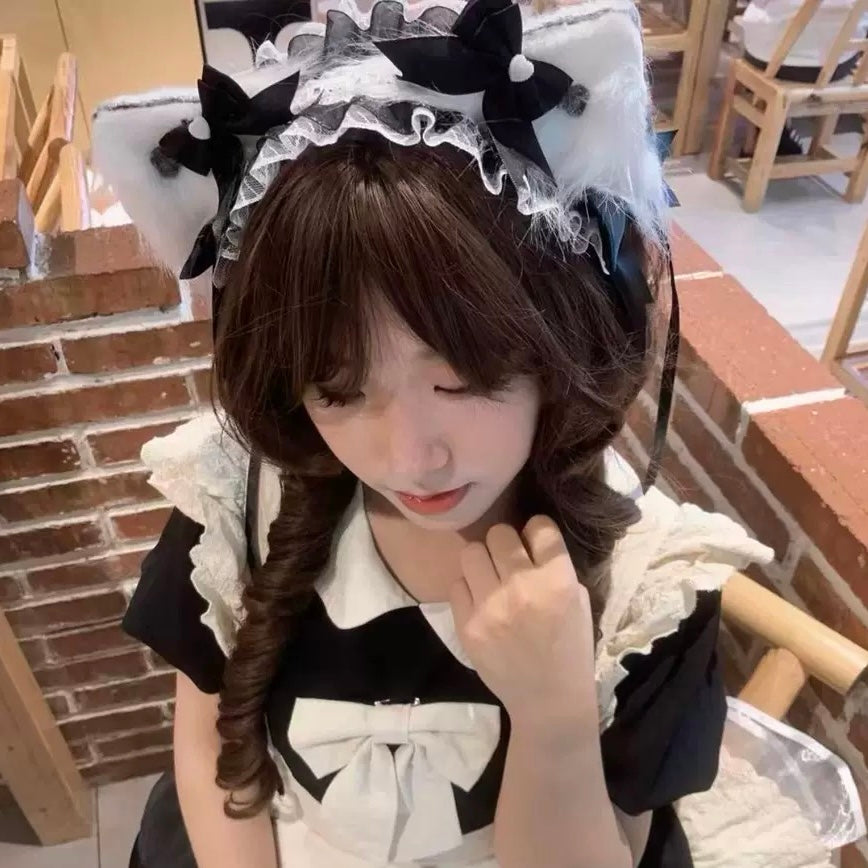 Person wearing a black and white maid outfit with decorative headband indoors.