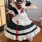 Person wearing a black and white maid outfit with red accents, posing indoors.