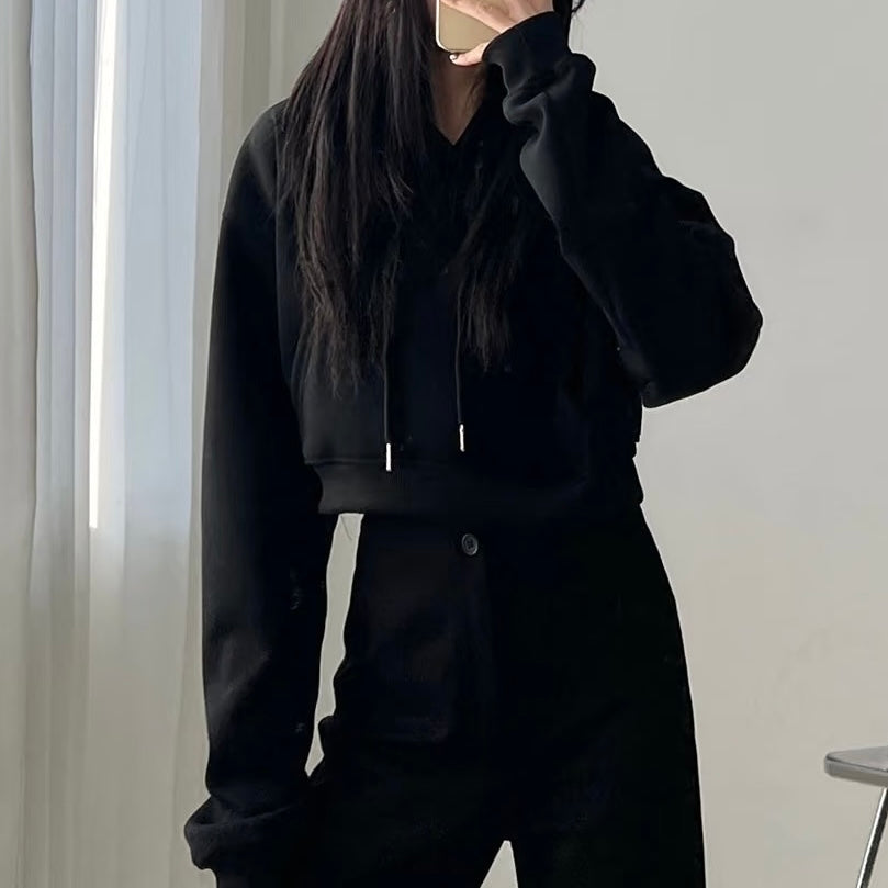 Femboy wearing a black hoodie and pants against a neutral background